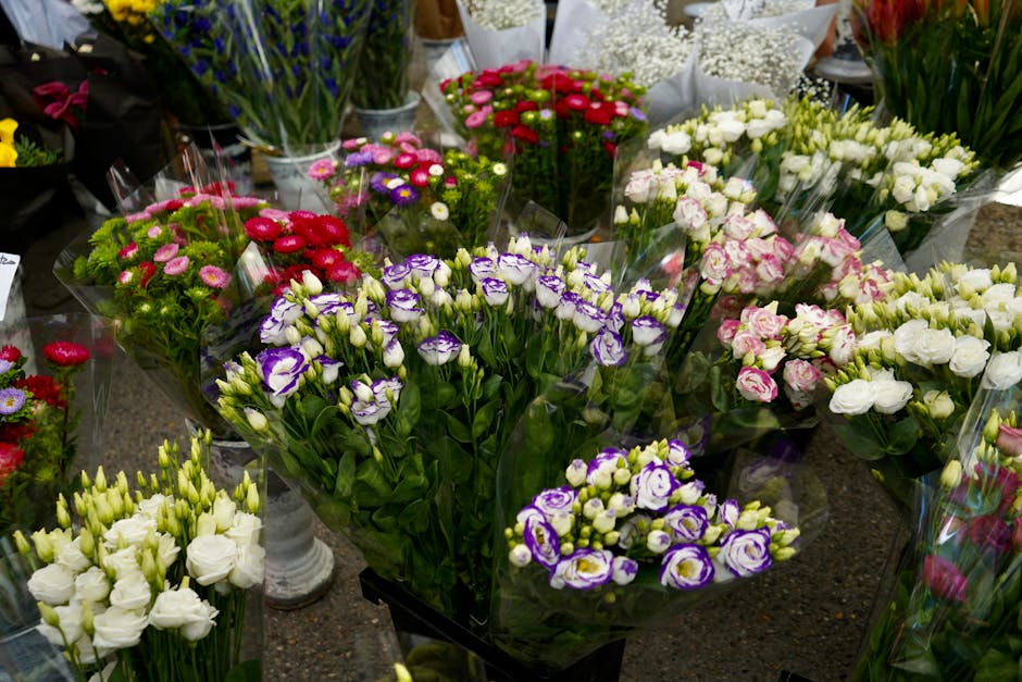 An assortment of fresh flower bouquets displayed on a table at a flower shop, featuring various vibrant blooms including purple and white lisianthus, pink and white roses, red and pink daisies, and wh